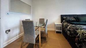 Une chambre à coucher comprenant un lit, une table de chevet, une chaise, un bureau et un miroir.