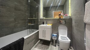 Une salle de bain moderne avec une douche à parois de verre, des toilettes blanches et un meuble-lavabo avec un miroir.