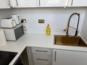 A kitchen with white cabinets, a stainless steel sink, a microwave, a toaster, and a bottle of Fairy dish soap. - Studio Sleeps 2 With Air Conditioning (Croydon)