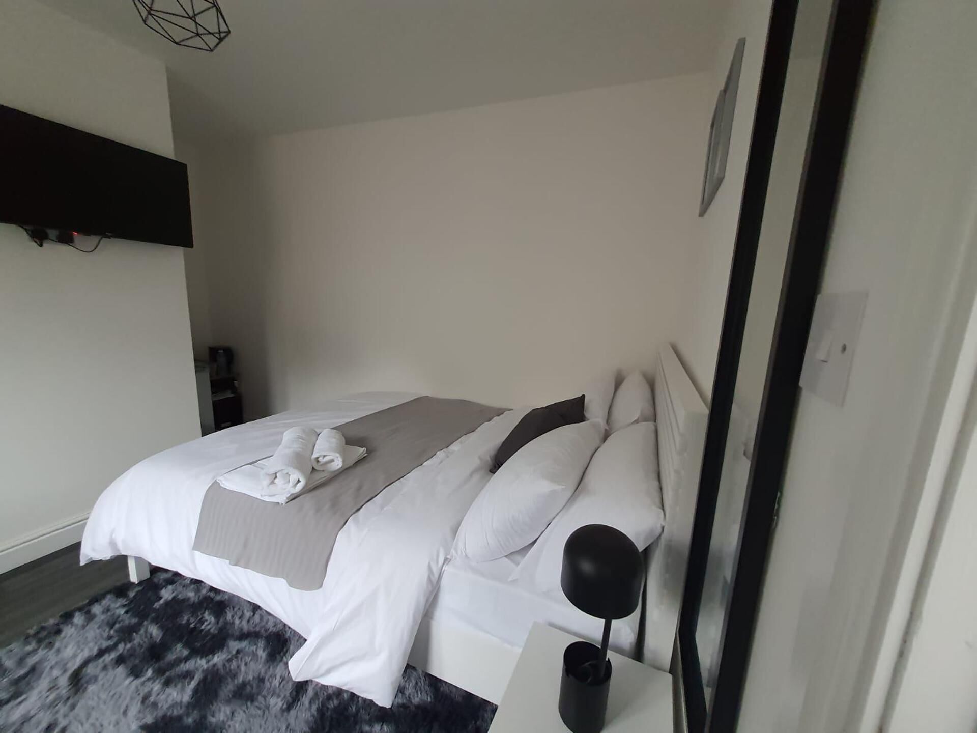 Ein zeitgemäßes Schlafzimmer mit Bett, Kissen, Nachttisch und Lampe.