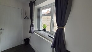 A narrow hallway with a radiator, a door, and a window with curtains. - Private Room, Sleeps 2 With Ensuite & Parking (Birmingham)