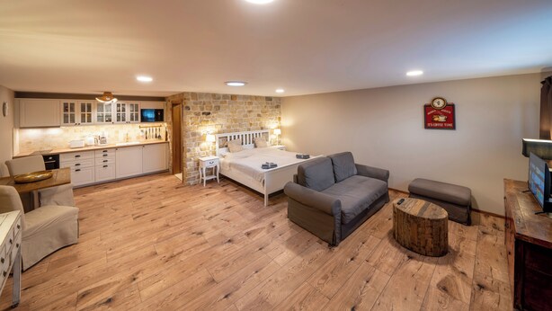 Un espacio habitable compacto con kitchenette, una cama, un sofá y una pequeña mesa redonda.