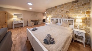 Un dormitorio con pared de piedra, una cama con toallas, un escritorio, una silla y un armario.