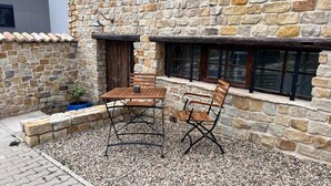 Un edificio de piedra con un patio que tiene una mesa de madera y dos sillas.