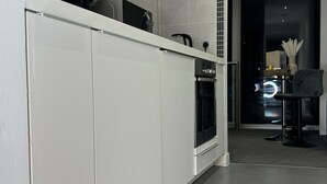 A modern kitchen with white cabinets, a built-in oven, and a coffee machine. - The Bullring Studio in Birmingham City Centre (Birmingham)