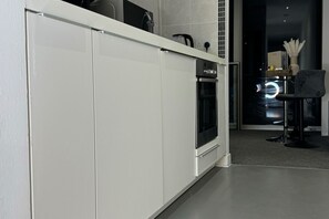 A modern kitchen with white cabinets, a built-in oven, and a coffee machine. - The Bullring Studio in Birmingham City Centre (Birmingham)