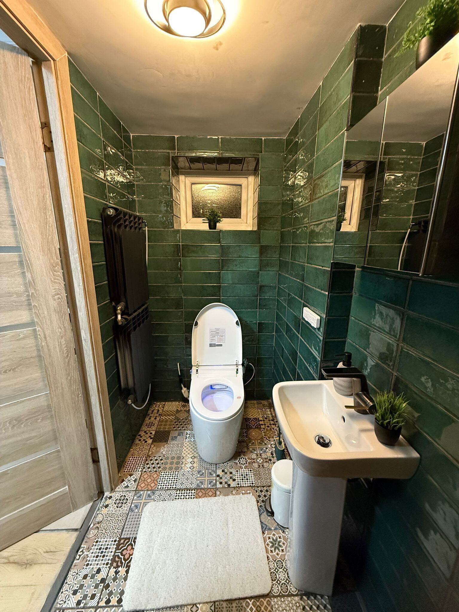A bathroom with a toilet, sink, and mirror.