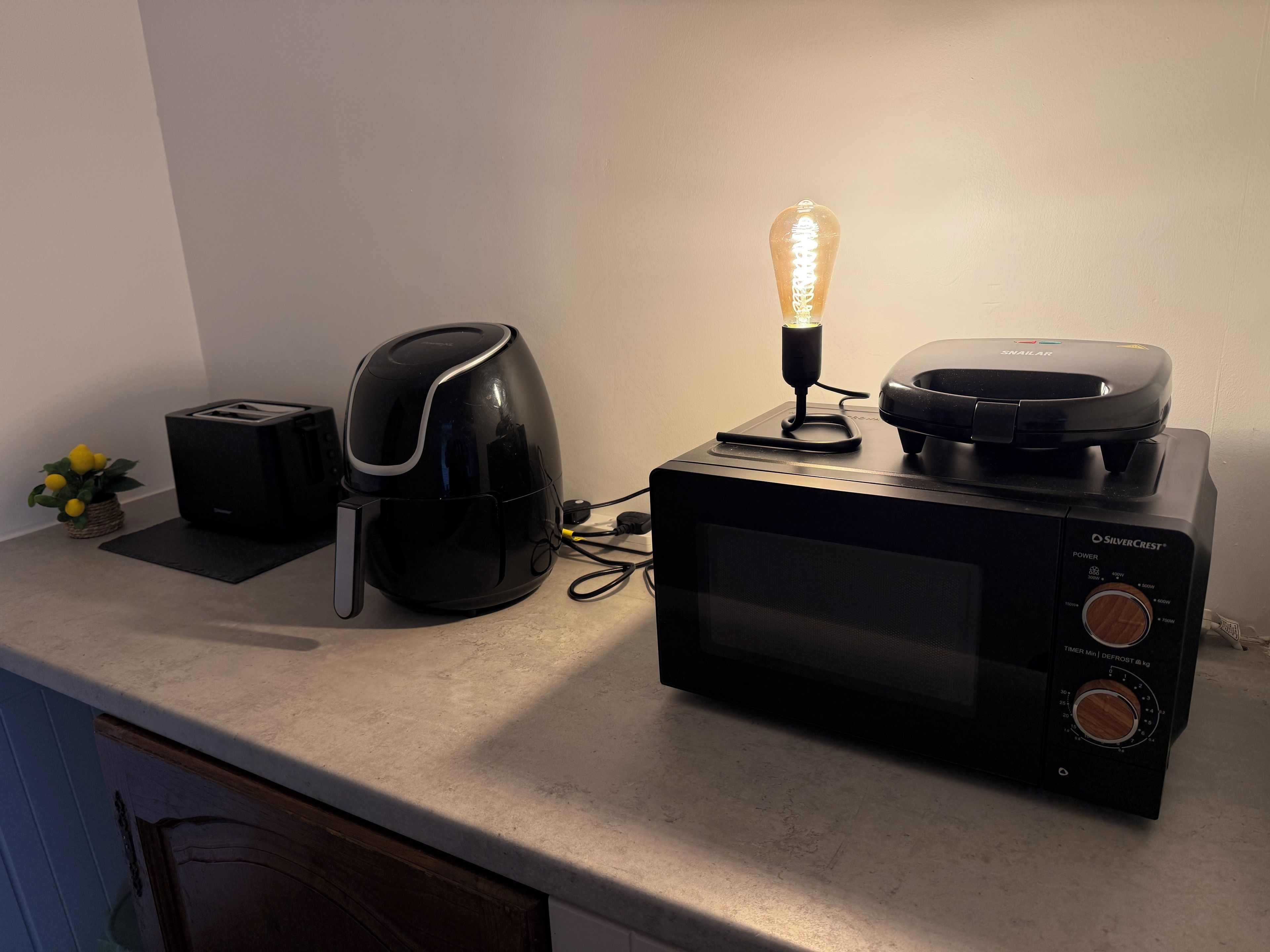 Una encimera de cocina con microondas, tostadora y cafetera.
