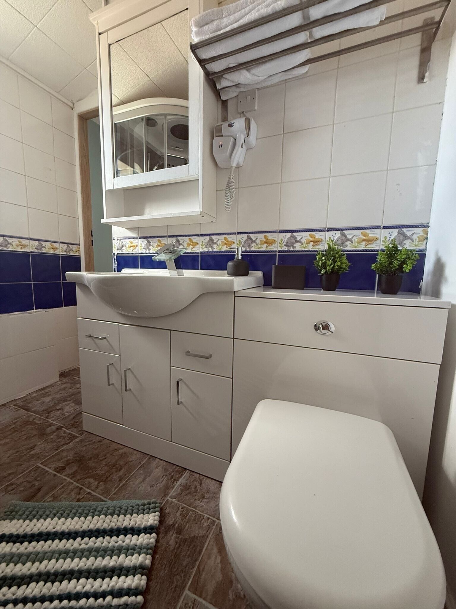 Une salle de bain avec un lavabo blanc, des toilettes et un meuble avec des tiroirs.