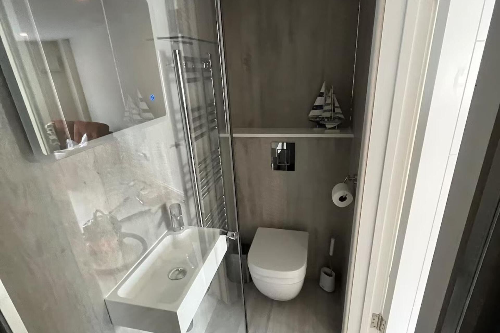 Un bagno piccolo e funzionale con cabina doccia in vetro, lavandino bianco e WC.