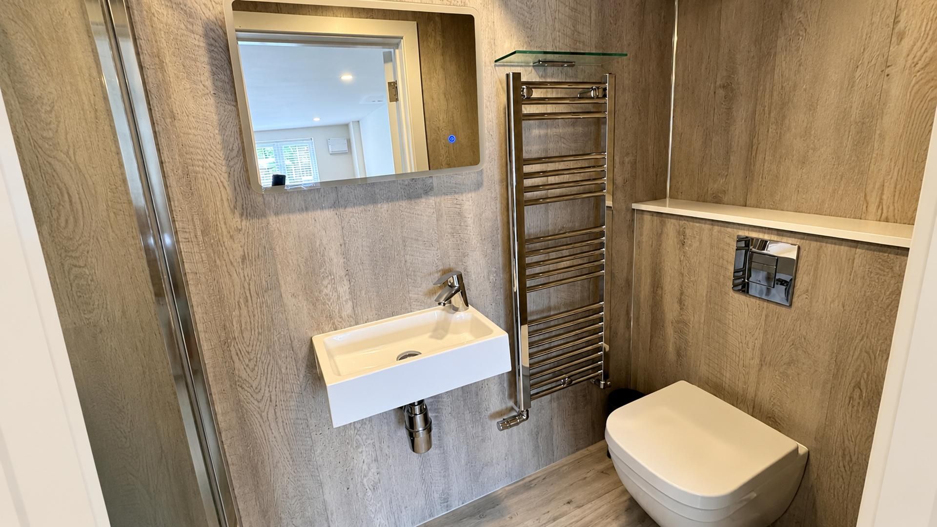 Een moderne badkamer met een inbouwgootsteen, een douchecabine van glas en een toilet.
