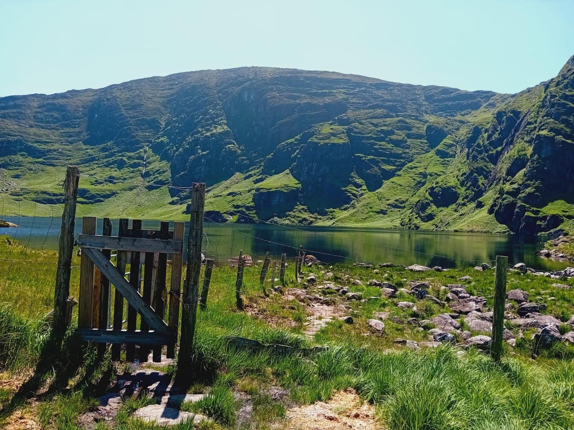 A wooden gate leading to a lake surrounded by mountains.