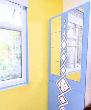 A room with a window, a yellow wall, and a blue door with a decorative pattern. - Cozy Studio Zulu, Central London (London)
