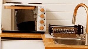Une cuisine compacte dotée d’un four encastré, d’un évier et d’un robinet en acier inoxydable.