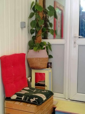 Eine gemütliche Ecke mit einem roten Sessel, einem kleinen Tisch mit einer Pflanze und einer Holzbank mit Kissen.