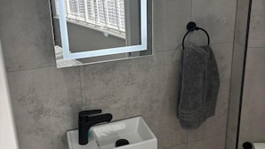 Een badkamer met een wit wastafel, een spiegel en een handdoekhouder.
