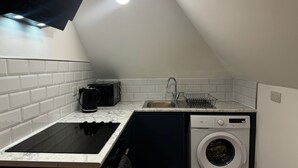 A compact kitchen with a built-in microwave, a sink, a dishwasher, and a washing machine. - Studio Flat In London (Bexleyheath)