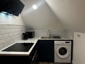 A compact kitchen with a built-in microwave, a sink, a dishwasher, and a washing machine. - Studio Flat In London (Bexleyheath)