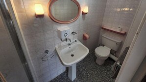 A bathroom with a white sink, a toilet, and a mirror with wall-mounted lights. - Studio Sleeps 1 - Pets Welcome -free Parking (Blackpool)