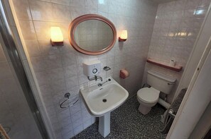 Ein Badezimmer mit einem weißen Waschbecken, einer Toilette und einem Spiegel mit Wandleuchten.