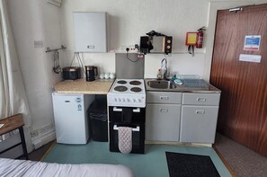 Eine kleine Küchenzeile mit Herd, Spüle und kleinem Kühlschrank.