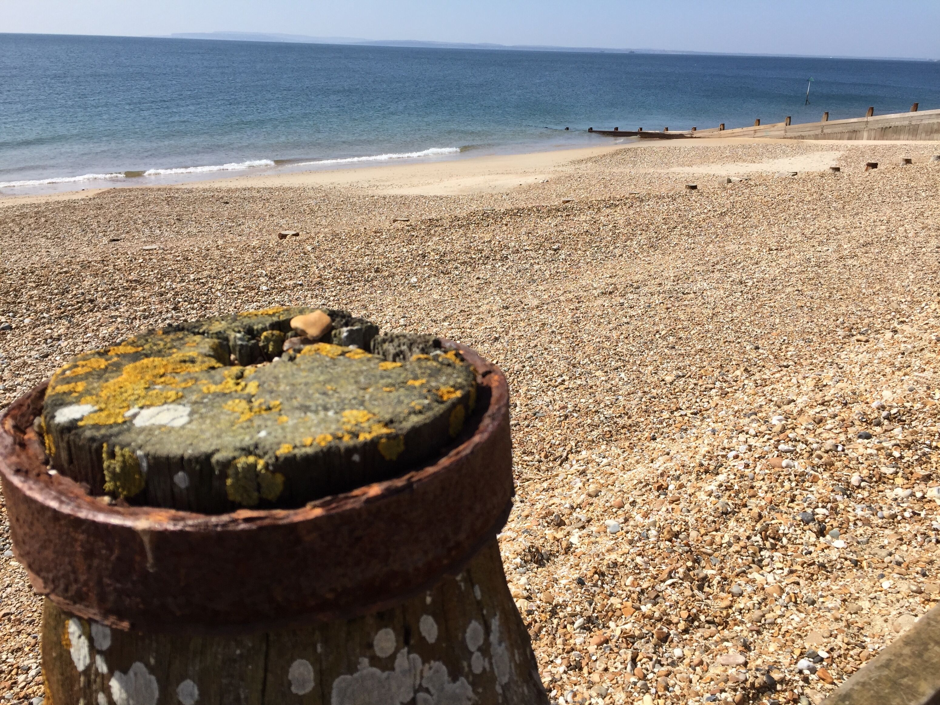 A pebbled beach with a rusty metal structure in the foreground.