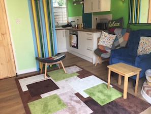 Ein gemütliches Wohnzimmer mit einem blauen Sofa, einem kleinen Holztisch und einem bunten Teppich.