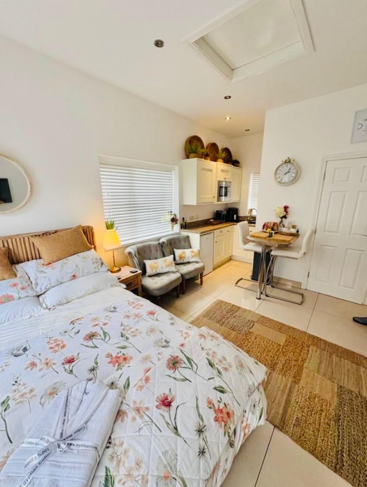 Un dormitorio con una cama grande, una silla, un escritorio y una kitchenette.