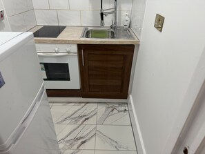 Eine kleine Küche mit einem weißen Kühlschrank, einem Herd, einer Spüle und Holzschränken.