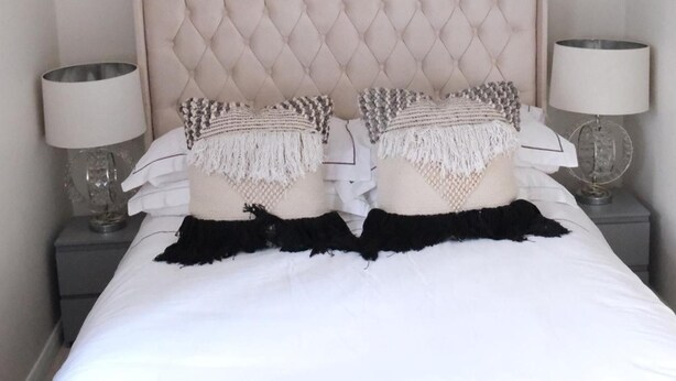 A bed with a tufted headboard, two decorative pillows, white bedding, and two bedside lamps. - Cosy Studio Getaway - Free Parking & Central Links (South Ockendon)