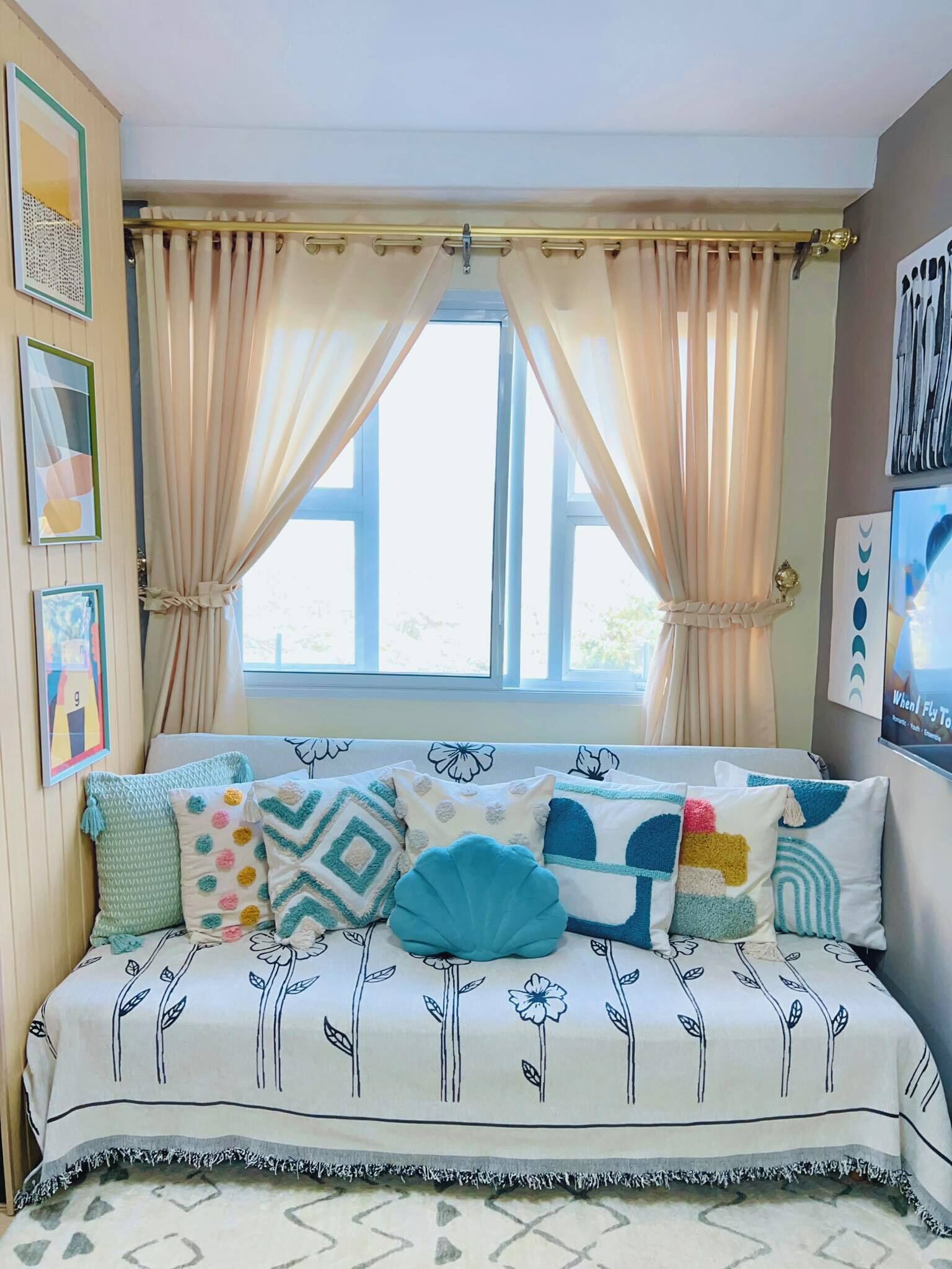 A cozy room with a bed, a window with curtains, and wall art.