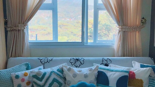 Un dormitorio con cama, ventana con cortinas y vista al exterior.