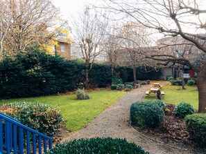 A garden with a gravel path, benches, and various shrubs. - London - Apartment - Riverside - Sleeps 3 - Garden (London)