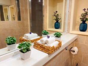A bathroom with a white countertop, two wicker baskets with white towels, and small potted plants. - London - Apartment - Riverside - Sleeps 3 - Garden (London)