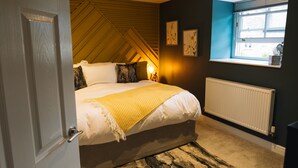 Un dormitorio con cama, ventana, radiador y puerta.