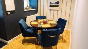Un comedor con una mesa redonda, sillas azules y un cuadro en la pared.