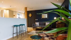 Una sala de estar moderna con un sofá, una mesa de centro y taburetes de bar.