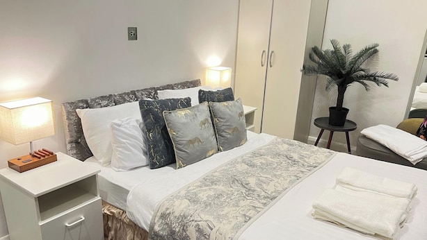 A neatly arranged bedroom with a bed, nightstands, a lamp, a small table with a plant, and a wardrobe. - Studio Sleeps 3 - Free Wifi - Flat-screen Tv (London)