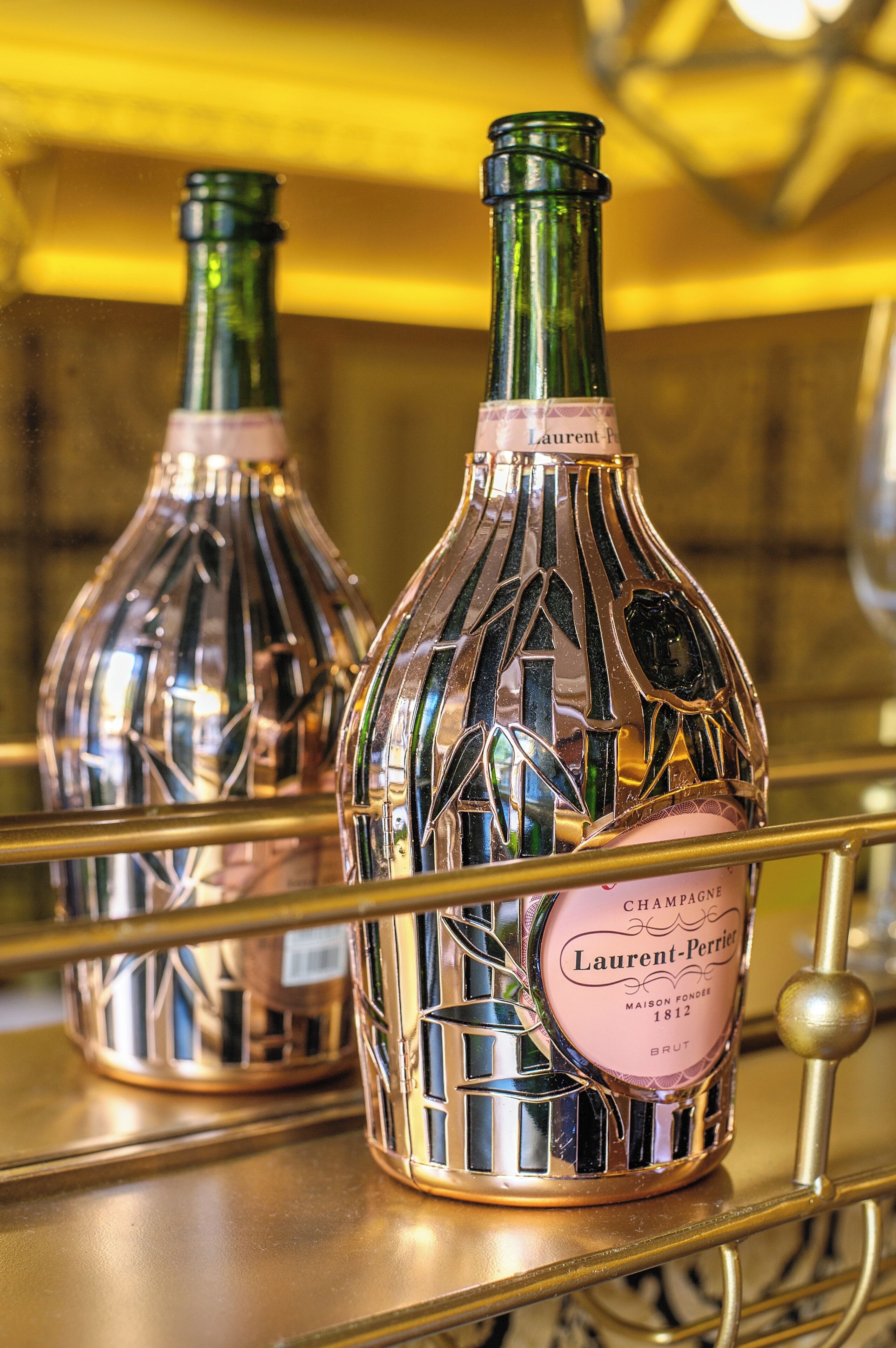 Dos botellas de champán sobre un estante dorado.