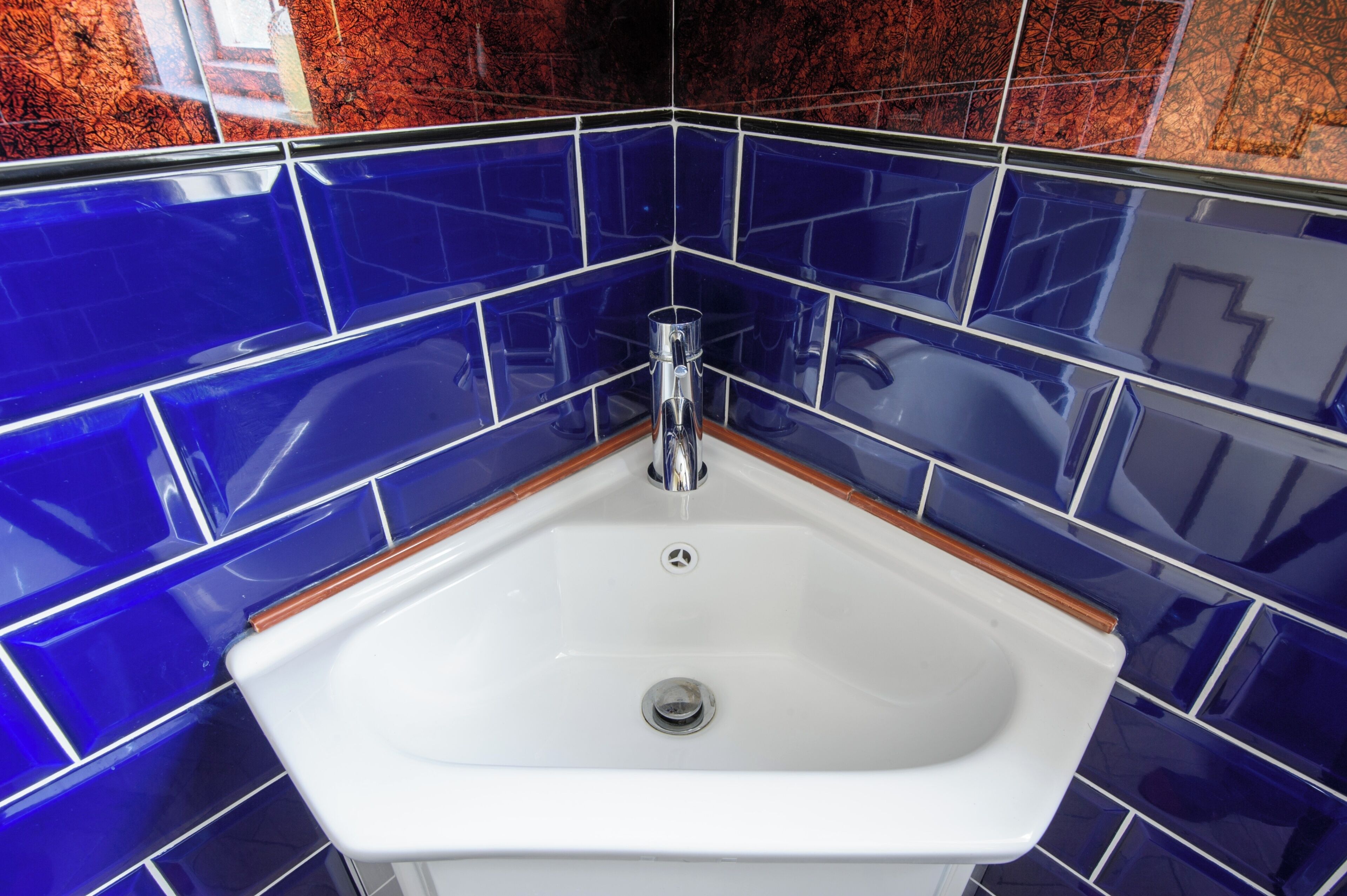 A bathroom with a white sink, chrome faucet, and blue-tiled walls.