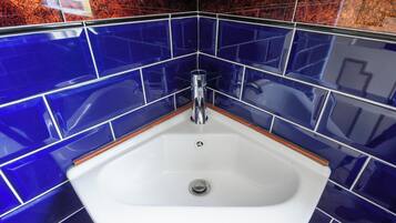 A bathroom with a white sink, chrome faucet, and blue-tiled walls.