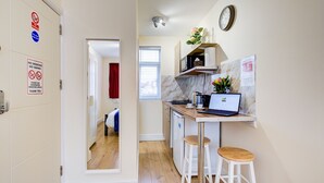 A compact kitchen with a laptop, stools, and a microwave. - Bright Cosy Studio & Free Parking-greater London (Enfield)