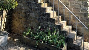 A stone building with a staircase leading to a door, surrounded by potted plants. - Hope Valley - Studio - Sleeps 2 - Parking (Hope Valley)