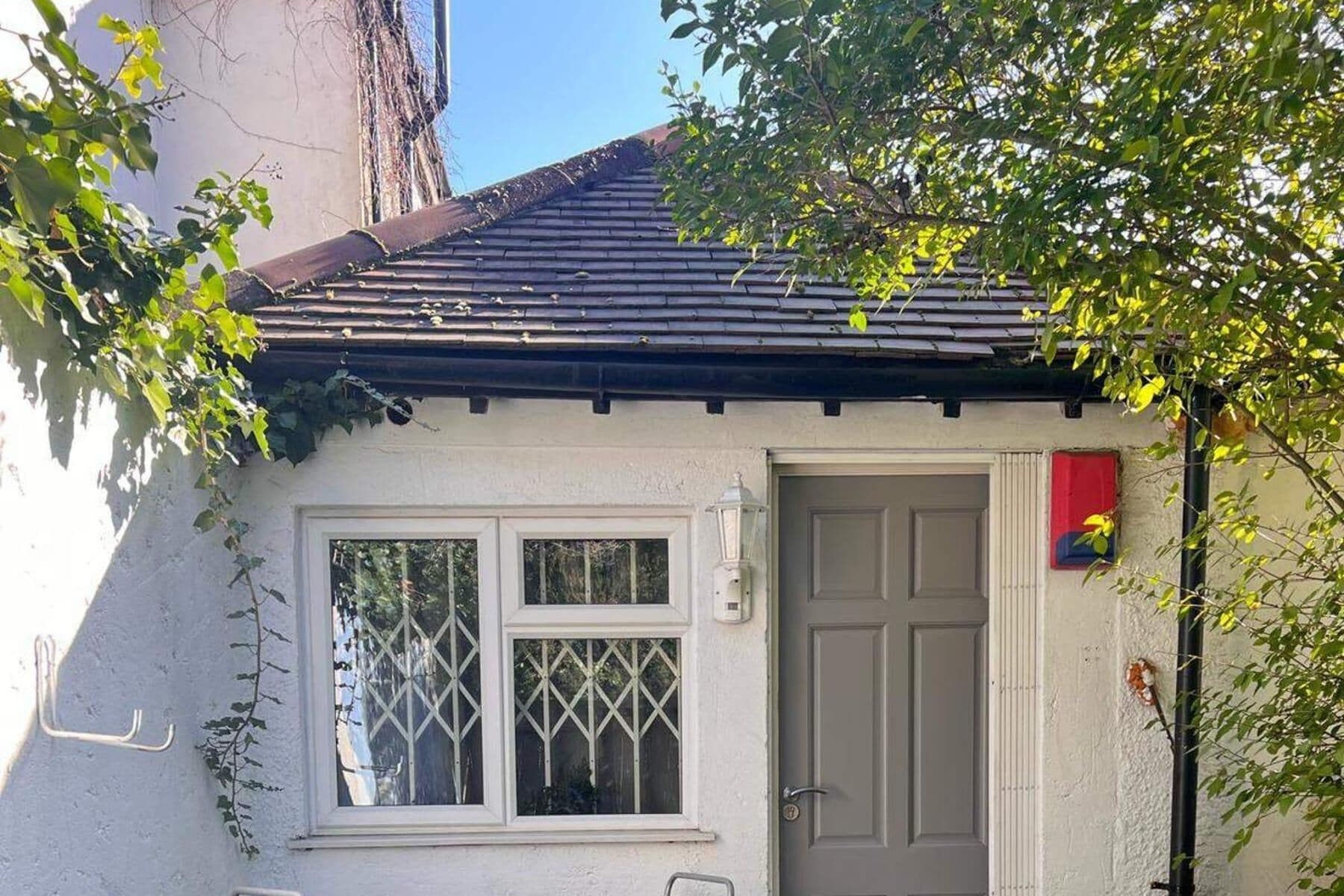 A small house with a tiled roof, a white door, and a window with a lattice design.