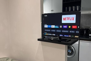 Televisor de pantalla plana muntat sobre un suport negre que mostra l'aplicació de Netflix i diversos altres serveis de streaming.