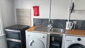 Une cuisine compacte équipée d’un four Bosch, d’un lave-linge et d’une machine à café.