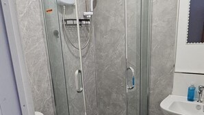 Une salle de bain avec une douche à parois de verre, des toilettes et un lavabo.