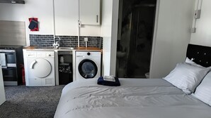 Une chambre d’hôtel équipée d’un lit, d’une machine à laver, d’un sèche-linge, d’un lavabo et d’une douche.