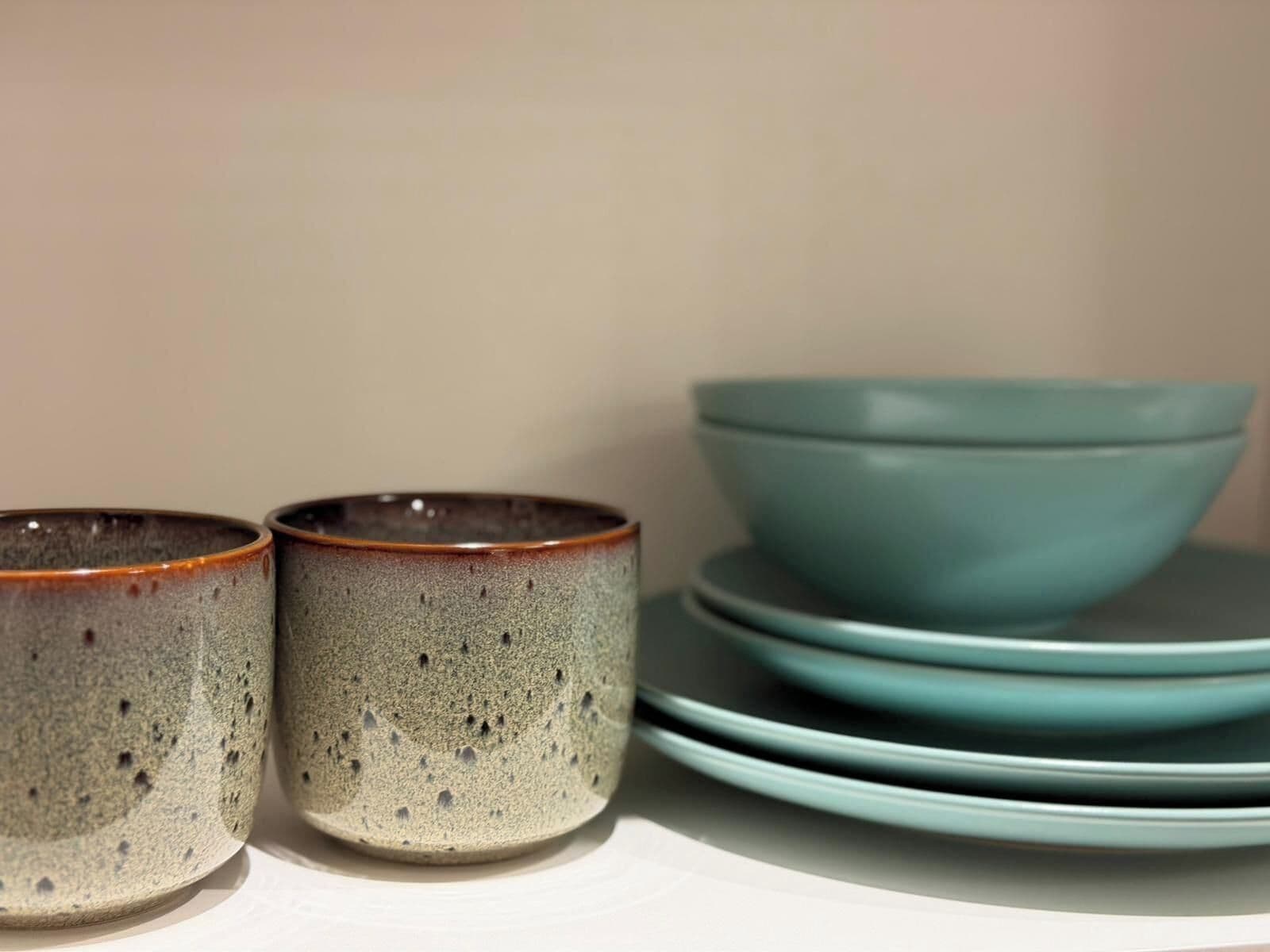 Una pila de tazones y tazas de cerámica sobre una estantería.