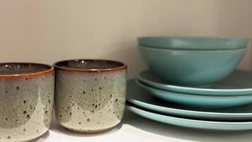 Una pila de tazones y tazas de cerámica sobre una estantería.